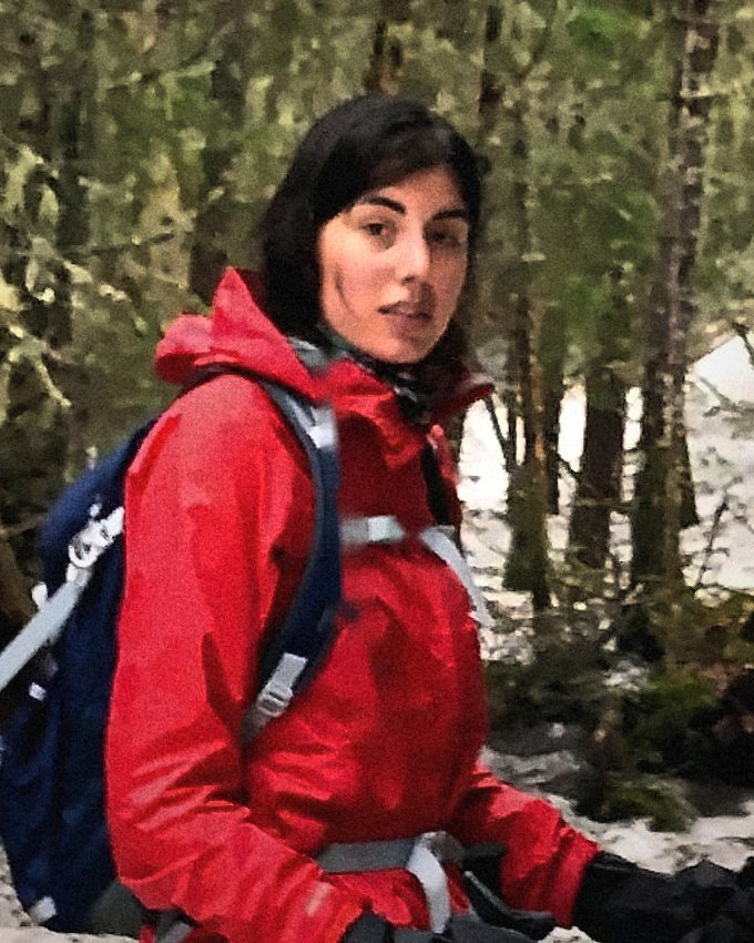 Christine Mehta, chest-up, in a red jacket on a snowy forest trail